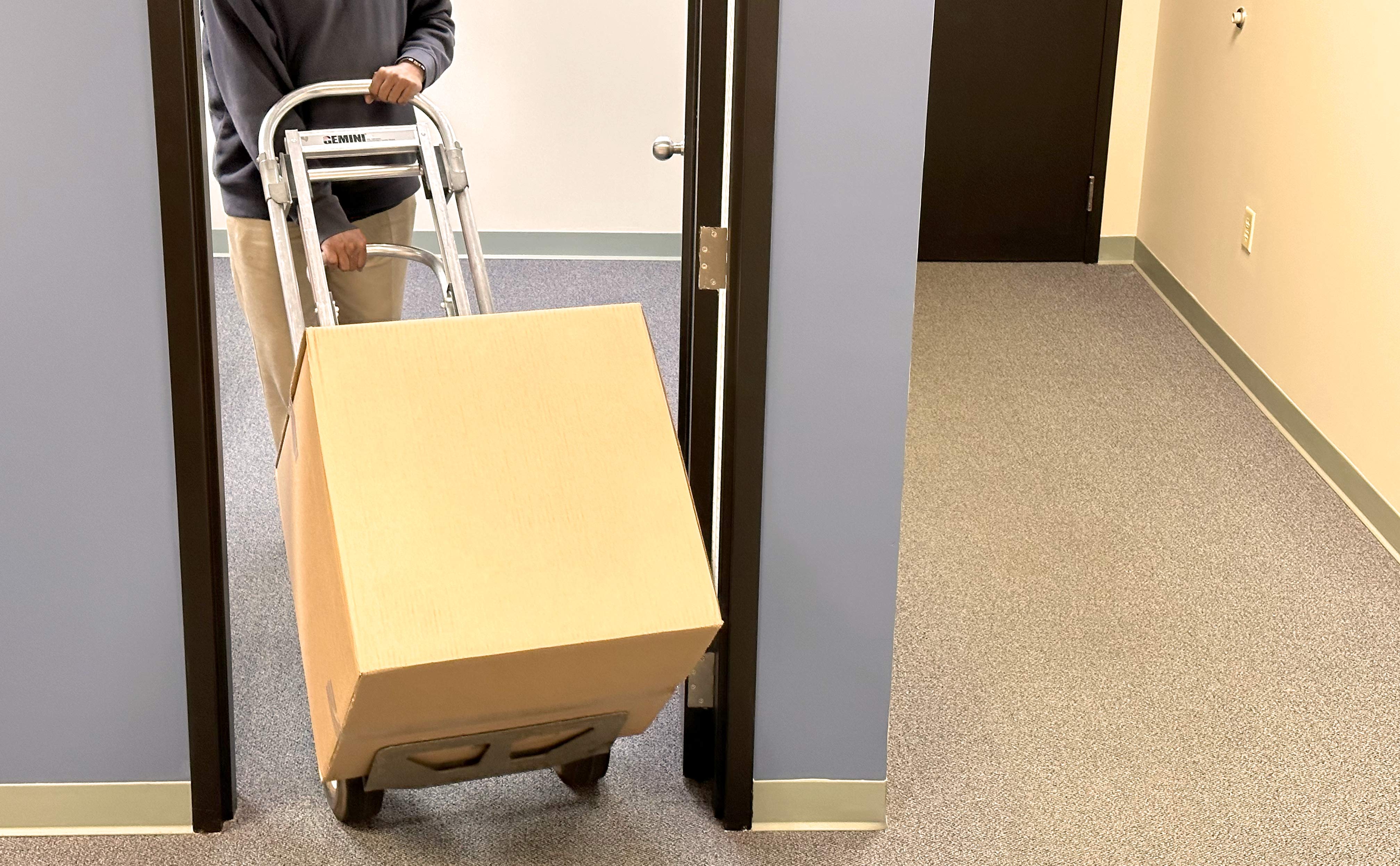 70 pound electronics recycle box on dolly - man pushing dolly with loaded box through an office doorway